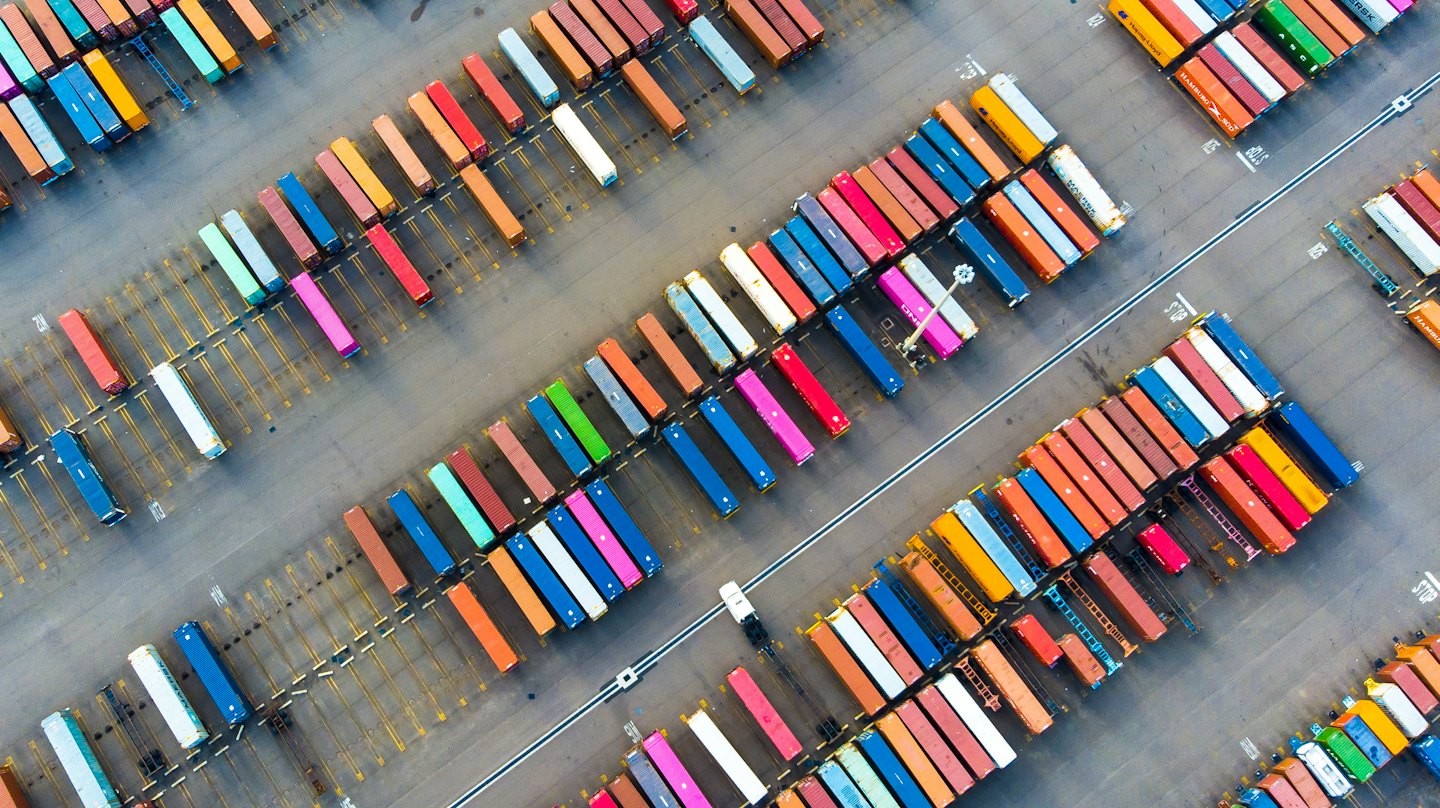 Colorful shipping containers arranged in rows at a logistics yard.